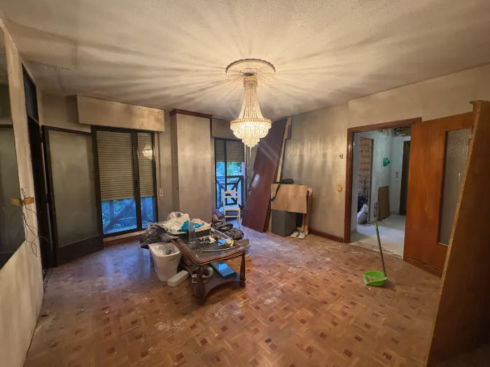 Salón antes de la reforma integral, con suelo de parqué gastado y paredes oscuras